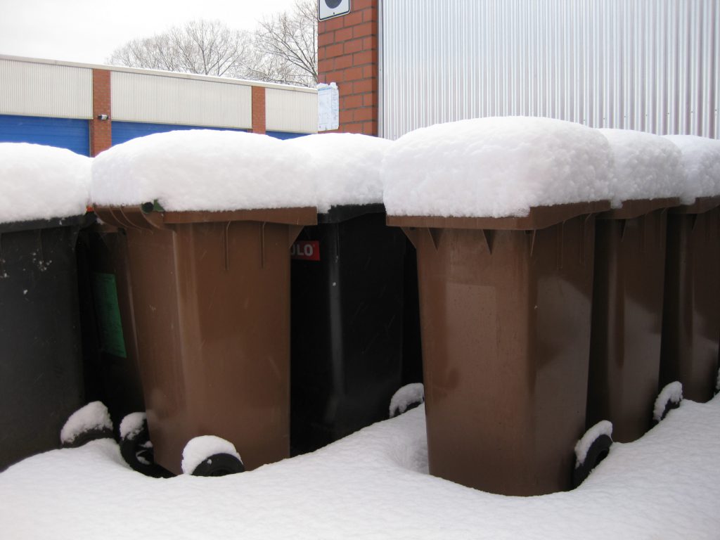 Muelltonnen unter einer Schneehaube im Winter